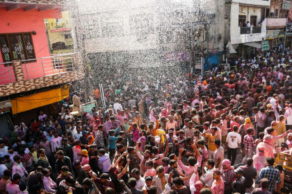 Mathura Holi celebration with devotees playing colors near temples.