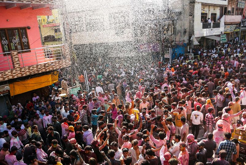 Mathura Holi celebration with devotees playing colors near temples.